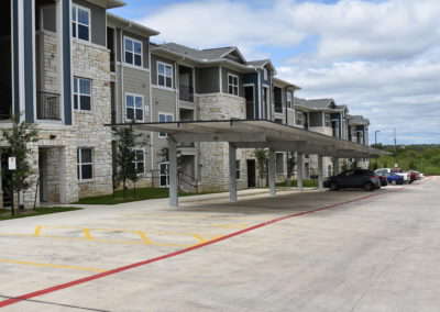 Exterior view of parking and residential buildings at Copper Pointe Apartments in San Antonio, TX