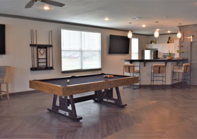 Resident lounge with pool table and televisions at Copper Pointe in San Antonio