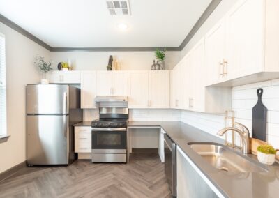 Model kitchen with stainless steel appliances and white cabinetry at Copper Pointe apartments