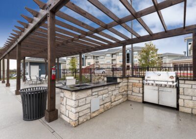 Outoor barbecue station and seating area under a pergula at our San Antonio, TX apartment community