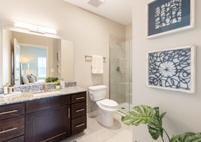 Model San Antonio, TX apartment bathroom with a granite vanity, large mirror, and shower