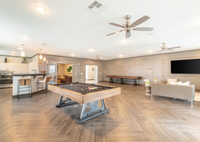 Resident community center with couches, kitchen, and pool table at Copper Pointe Apartments