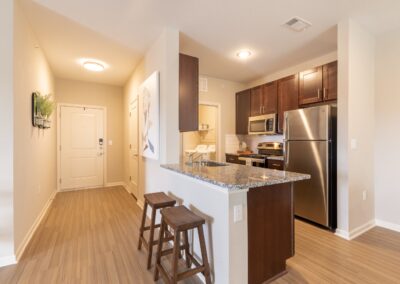Model kitchen with barstools and granite countertops at Copper Pointe Apartments