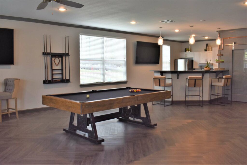 Community room with pool table, kitchen with refrigerator and oven, and breakfast counter with seating